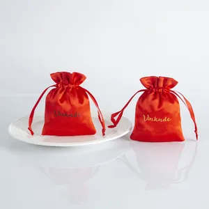 Close-up of red satin drawstring bags with Vinknde logo for jewelry gift packaging