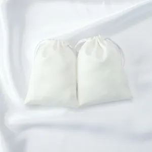 Close-up view of two elegant white satin drawstring pouches for jewelry or accessories