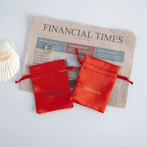 Close-up detail of smooth red satin drawstring gift pouches with custom logo branding.