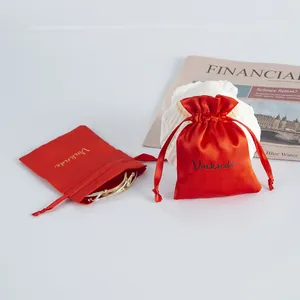 Red satin drawstring gift pouches for jewelry with elegant seashell and newspaper props