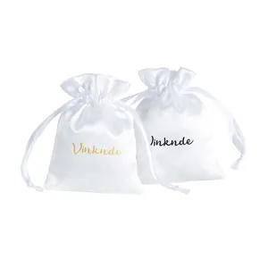 Two elegant white satin drawstring jewelry pouches with signature gold and black branding.