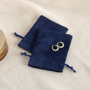 Detailansicht marineblauer Samtbeutel für Schmuck mit eleganten Perlenohrringen als Akzent