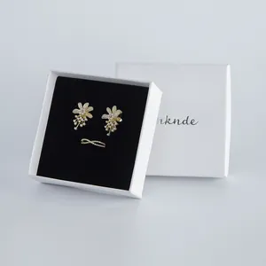 Weiße Schmuckschachtel mit eleganten Perlenblumenohrringen und einem Ring-Set