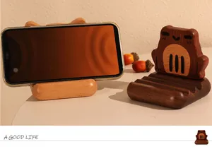 Nahaufnahme von Frosch- und Katzen-Handyhaltern aus Holz in hellen und dunklen Tönen.