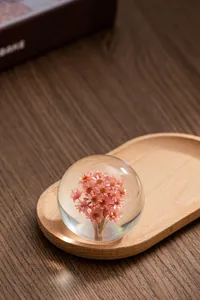 Gros plan détaillé d'une boule de cristal avec des fleurs roses sur un plateau en bois