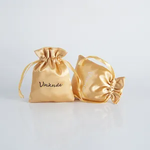 Macro view of champagne gold satin drawstring storage pouches for jewelry and accessories