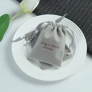 Close-up of elegant grey velvet jewelry pouches with ribbon drawstring closure on a white plate