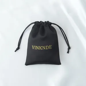 Vista detallada de una bolsa de regalo de satén negro con un elegante logo dorado