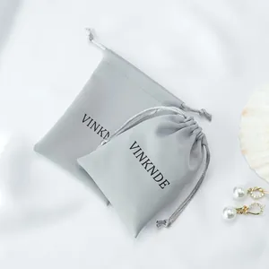 Close-up detail of silky grey satin drawstring storage bags with black printed logo