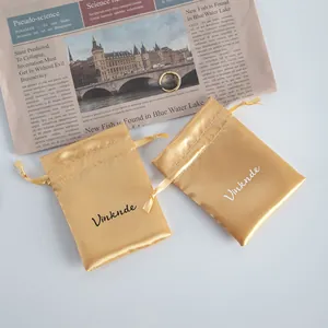 Close-up of golden satin drawstring pouches for jewelry storage on newspaper background