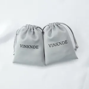 Detail view showing two light gray silk satin drawstring bags with printed VINKNDE logo