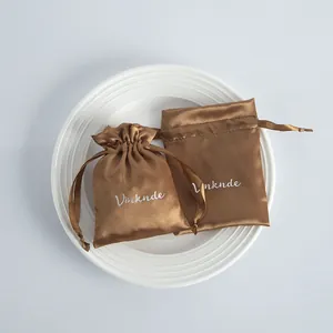Detailed close-up of brown satin drawstring jewelry pouches on a white ceramic plate