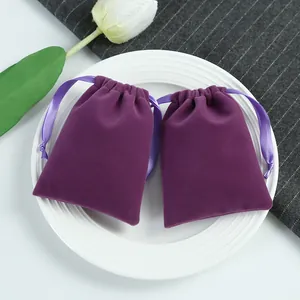 Gros plan de deux pochettes en velours violet avec cordon sur une assiette blanche pour cadeaux