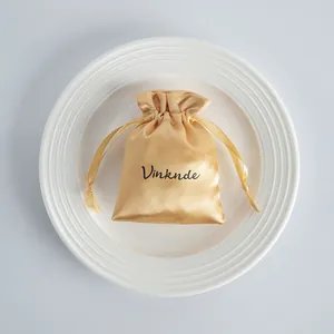 Detailed view of a premium champagne satin drawstring jewelry pouch on a white plate.