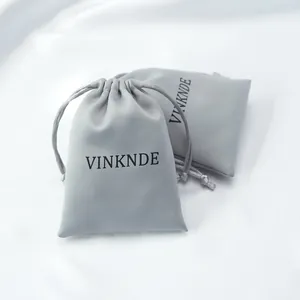 Macro detail of two grey smooth satin drawstring pouches showing silk fabric texture