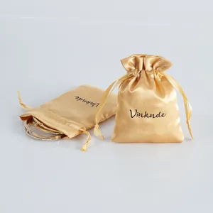 Close-up detail of luxurious gold satin drawstring jewelry pouches with glossy silk texture