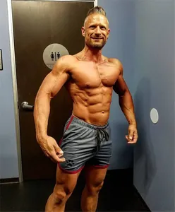 Detail view of men's gray mesh gym shorts with red trim and paw print on fitness model