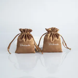 Detailed view of two gold satin drawstring jewelry gift bags with silky texture