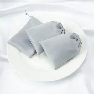 Detailed view of grey silky satin drawstring storage bags on white plate