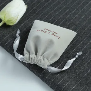 Close-up shot of a luxury grey velvet jewelry drawstring pouch with satin ribbons