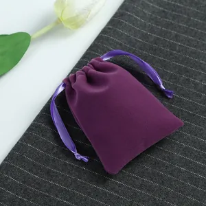 Détail d'une pochette en velours violet avec cordon de serrage sur tissu gris