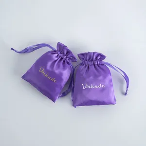 Two elegant purple satin drawstring pouches for jewelry and cosmetic storage with brand logo