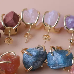 Detailed macro view of raw crystal stud earrings featuring gold-plated prong settings