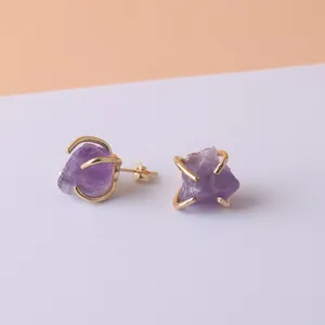 Detail of raw amethyst crystal stud earrings with gold-plated four-claw setting.