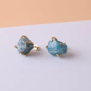 Close-up of raw blue crystal stud earrings with gold-plated four-prong settings