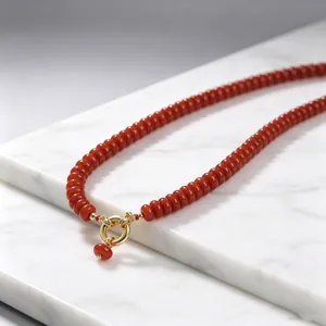 Detalle de un collar de piedras rojas con un elegante cierre de marinero dorado y sofisticado.