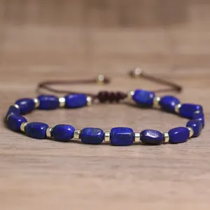Close-up of blue natural stone beads and gold spacers on a braided cord bracelet
