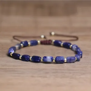 Detailed view of a handmade natural blue stone bracelet with gold spacers on wood