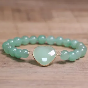 Macro view of a green heart stone centerpiece on an 8mm natural stone beaded bracelet.