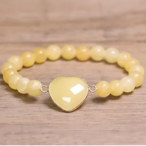 Detailed view of a light yellow natural stone beaded bracelet with a heart-shaped charm