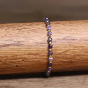 Detailed macro view of faceted purple amethyst and gold spacer beaded bracelet.