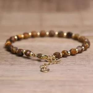 Macro view of handmade natural stone beaded bracelet featuring gold-plated lobster clasp
