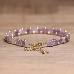 Detailed macro view of a handmade TILA bead woven bracelet with purple amethyst stones