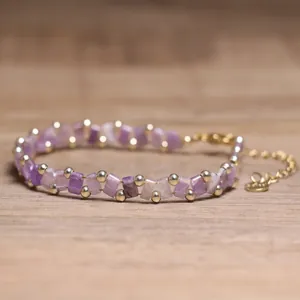 Macro detail of handmade purple Tila bead bracelet with delicate gold metallic accents