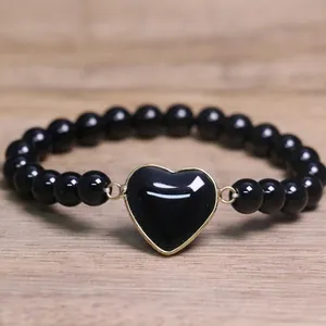 Detailed view of a black 8mm beaded bracelet with a centered black heart pendant