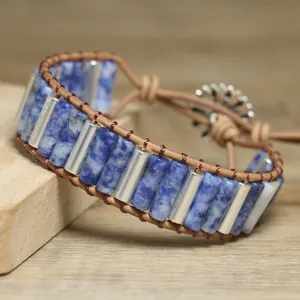 Detail shot of blue stone and leather wrap bracelet with silver tubes on wood surface
