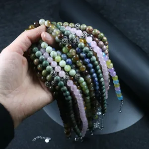 Mano sosteniendo varios collares de cuentas de piedra natural con cuarzo y ágata.
