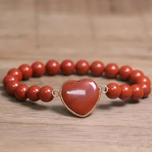 Close-up of red natural stone beaded bracelet with heart-shaped stone centerpiece
