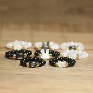 Detail of handmade beaded rings with pearlescent cat and rabbit shell motifs.