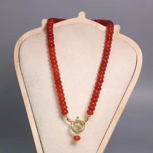 Detalle del collar de cuentas de piedra natural roja con cierre marinero dorado