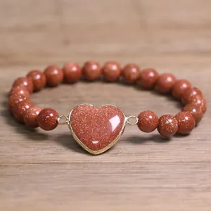 Detailed view of 8mm goldstone beaded bracelet featuring a sparkling heart-shaped pendant.
