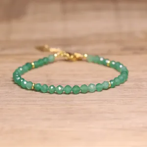 Close-up of bohemian faceted green natural stone beaded bracelet with gold spacers.