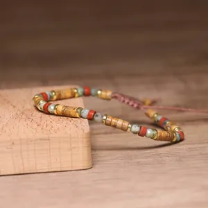Close-up detail of a handmade 2x4mm natural stone bead bracelet with adjustable woven cord.