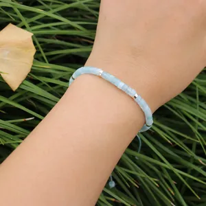 Detailopname van verstelbare aquamarijn stenen kralenarmband op pols tegen groene gras.