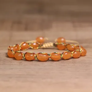 Detailed view of handmade woven bracelet with orange oval natural stone beads