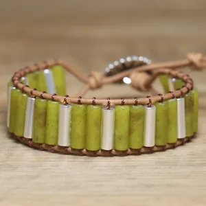 Detailed view of olive green stone cylinders and silver tubes on a woven bracelet.